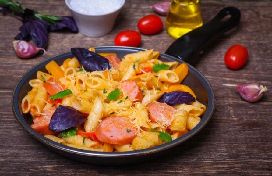 A bowl of pasta with vegetables on the side.