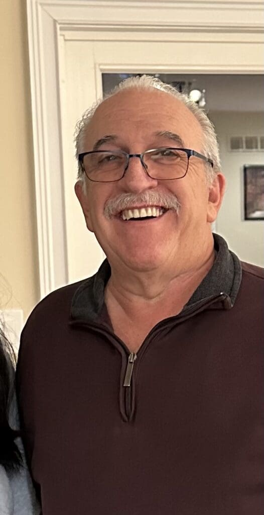 A man with glasses smiling for the camera.