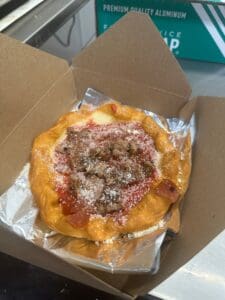 A pizza sitting in an open box on top of foil.